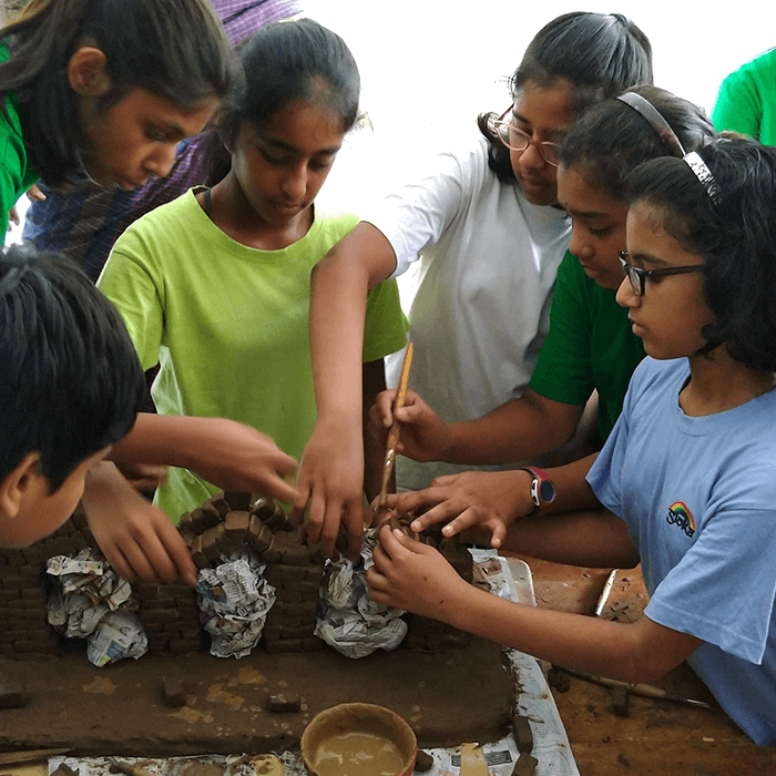Students grouped around a table working together with clay.