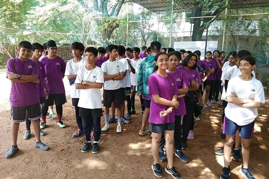 Several students stand in rows outdoors during P.E.